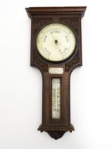 An early 20thC carved oak cased barometer / thermometer with presentation plaque engraved '