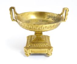 A 19thC gilt bronze tazza of twin handled urn form on a squared base with bun feet. Approx. 5 1/4"