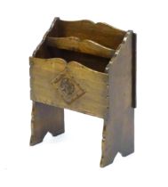 An early / mid 20thC oak magazine rack with a carved rosette within a carved lozenge to the front.