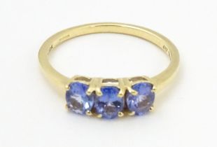 A 9ct gold ring set with three blue stones. Ring size approx. N Please Note - we do not make