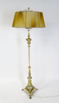 A gilt four branch standard lamp with cherub head detail raised on a triform base with paw feet.