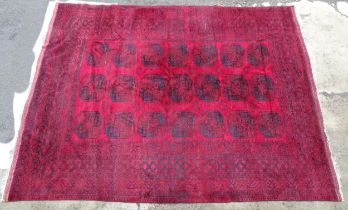 Carpet / Rug : A red ground Afghan carpet decorated with repeating medallions and banded geometric
