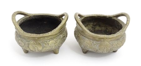A pair of small Chinese brass twin handled censers decorated with dragons and flowers, raised on