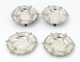 Four silver dishes with embossed decoration, two raised on three out swept feet, hallmarked