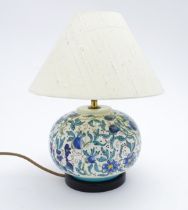 A ceramic table lamp of globular form decorated with scrolling floral and foliate decoration.