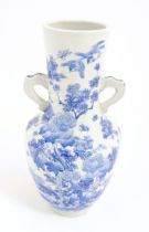 A Japanese blue and white twin handled vase with hand painted decoration depicting birds, flowers