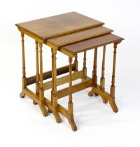 A nest of three early 20thC walnut tables each with a rectangular top, four turned pillar supports