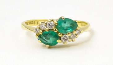 An 18ct gold ring set with two emeralds and six diamonds. Ring size approx. N Please Note - we do