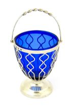 A Victorian sugar basket with openwork decoration, swing handle and blue glass liner, hallmarked