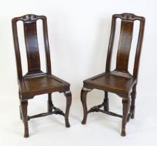 A pair of early 18thC oak side chairs, with carved top rails decorated with scrolls and floral