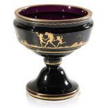 A SMALL BLACK AMETHYST PEDESTAL VASE WITH OVERLAID GILT DECORATION OF CHILDREN FROLICKING