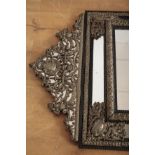 A CHARLES II STYLE REPOUSSE WHITE METAL AND EBONISED WOOD MIRROR