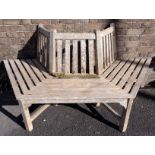 A THREE-SIDED WEATHERED TEAK TREE BENCH