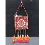 A SMALL CARPET BAG WITH LONG TASSELS