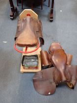 THREE LEATHER SADDLES, ON A STAND,