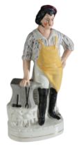 A VICTORIAN STAFFORDSHIRE POTTERY FIGURE OF A BLACKSMITH