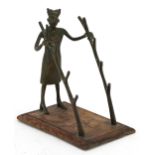 Tribal interest bronze pen-rest on hardwood stand in the form of a tribesman holding two trunks,