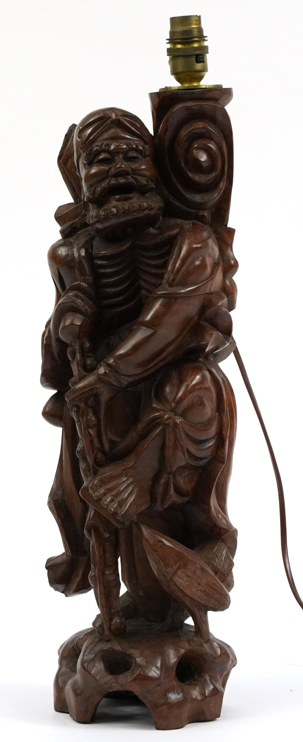 Chinese root wood lamp base carved in the form of an elder holding a staff, 53.5cm high