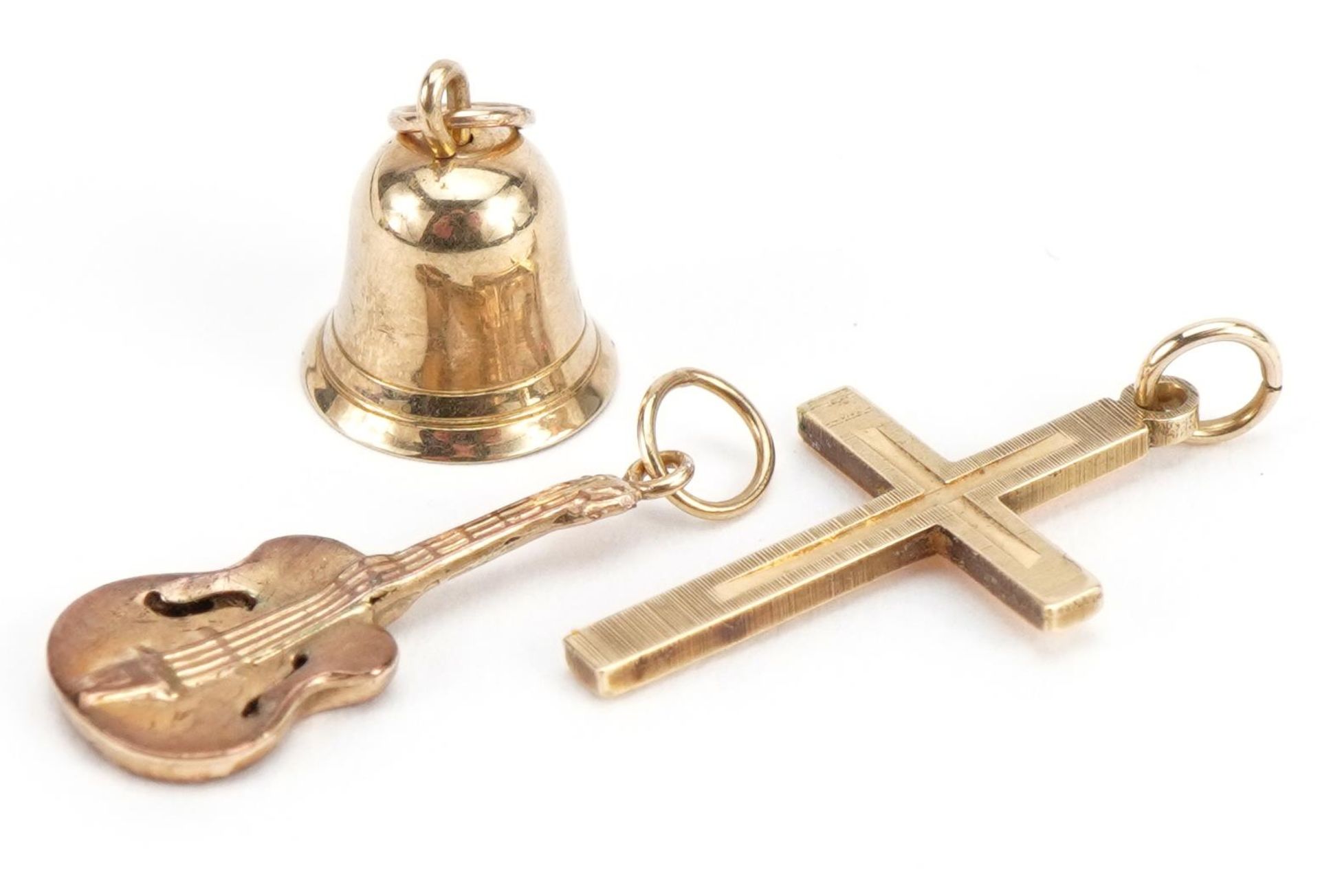 Three 9ct gold charms comprising cross, bell and guitar, the largest 2.3cm high, total 2.1g