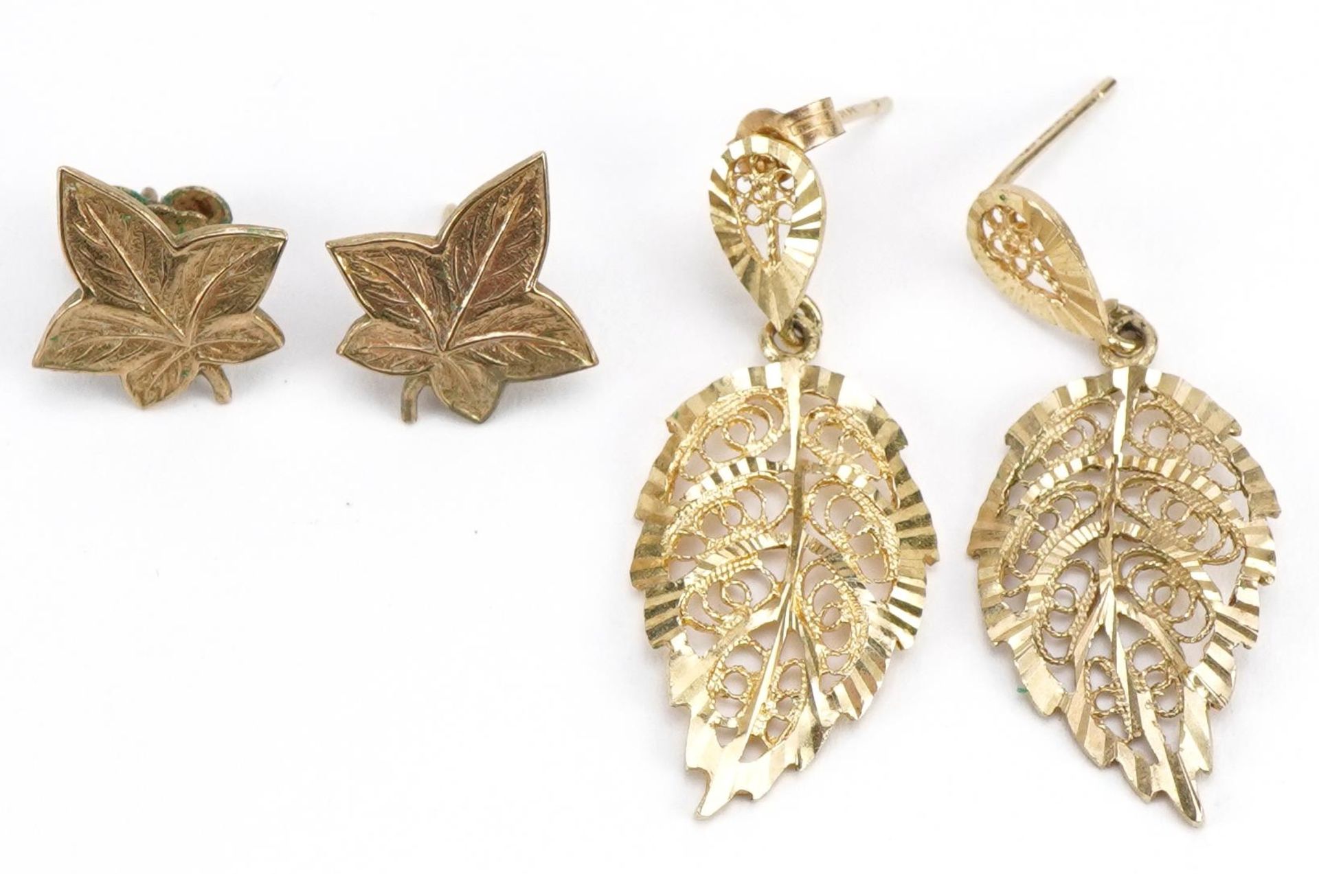 Two pairs of 9ct gold leaf design earrings including a pair of maple leaf studs, the largest 3.5cm