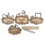 Four silver decanter labels and a silver and mother of pearl folding pocket knife, the largest 7cm