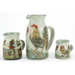 Colin Kellam, Three studio pottery jugs hand painted with cockerels and fish, the largest with