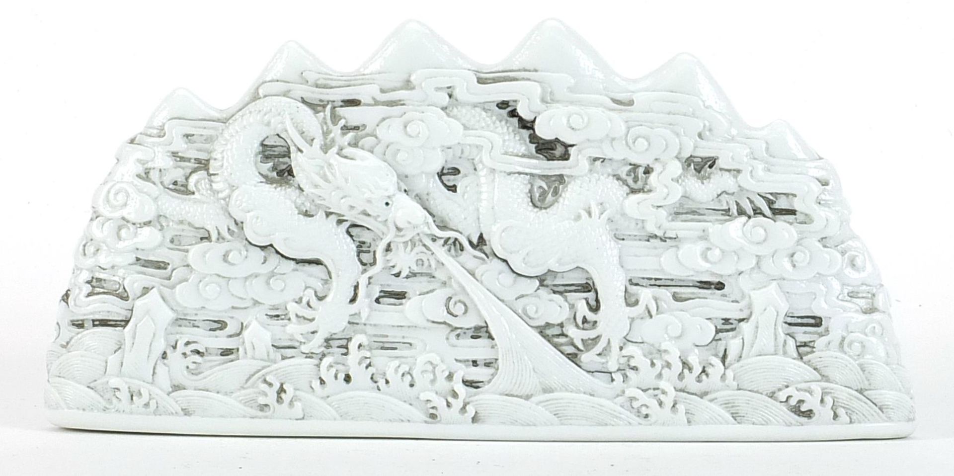 Chinese blanc de chine porcelain scholar's brush rest decorated in relief with dragons amongst