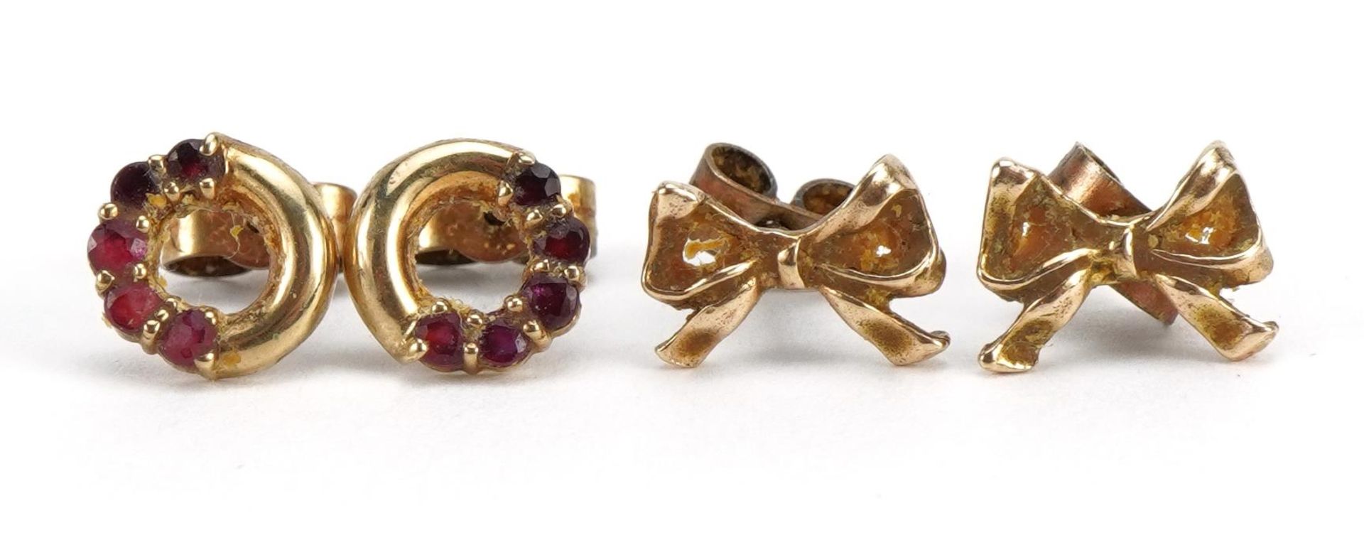 Two pairs of 9ct gold earrings, one set with rubies and bow design studs, the largest 1.0cm wide,