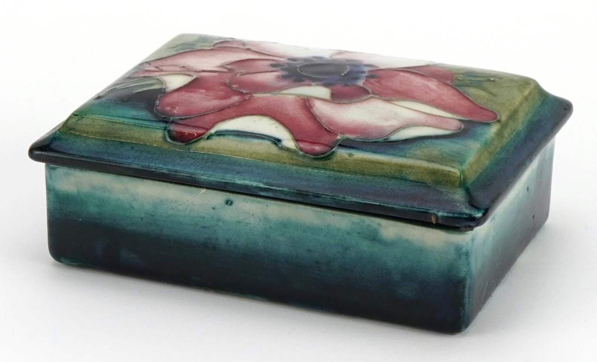 William Moorcroft pottery box and cover hand painted with a flower head, 12cm wide