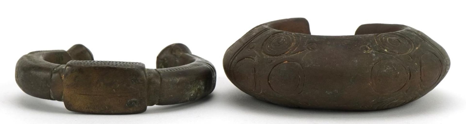 Two Middle Eastern bronze slave bangles with incised decoration, the largest 10cm wide