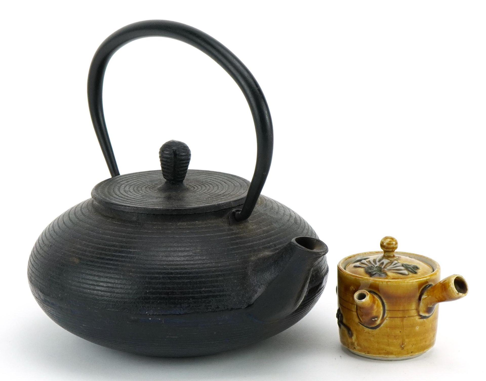 Oriental cast iron teapot and a pottery example, the largest 18cm in length
