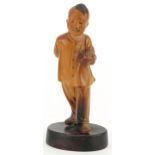 Chinese boxwood carving of a young boy holding a fruit, raised on an oval base, 11cm high