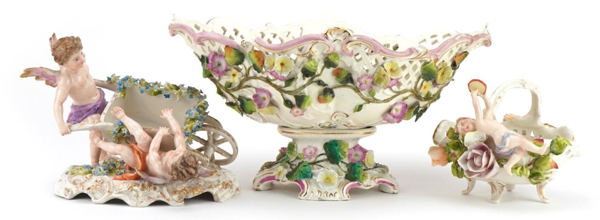 German floral encrusted porcelain including a centrepiece and four footed basket with Putti, the