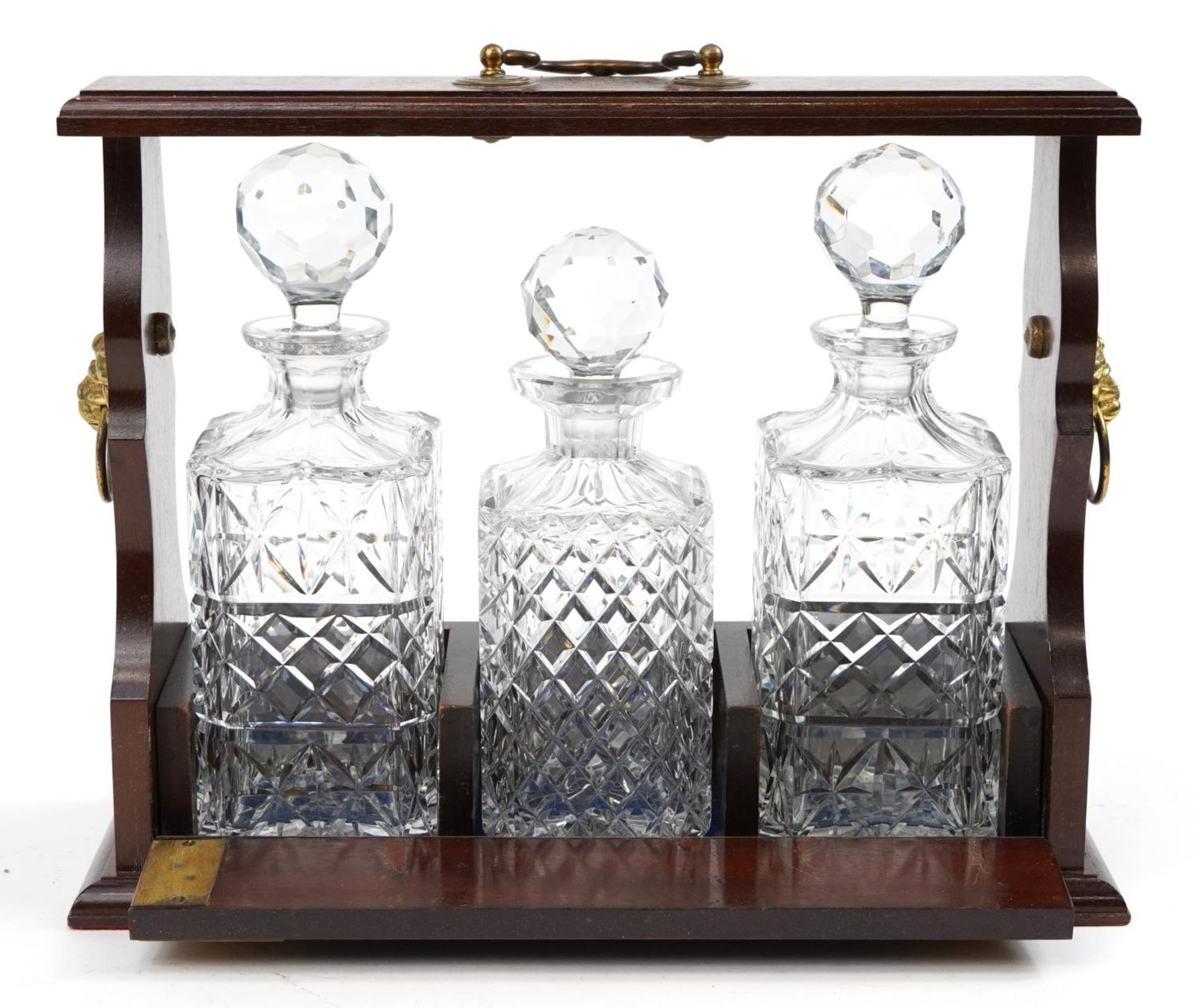 Mahogany three bottle tantalus with brass ring turned lion head handles and three glass decanters, - Bild 2 aus 3