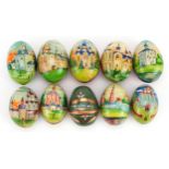 Ten Russian hardwood eggs hand painted with buildings and Cyrillic script, the largest approximately