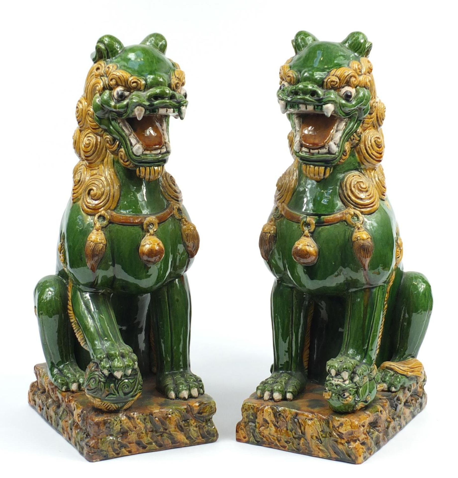 Large pair of Chinese floor standing pottery seated lions having a sancai type glaze, each 59cm high