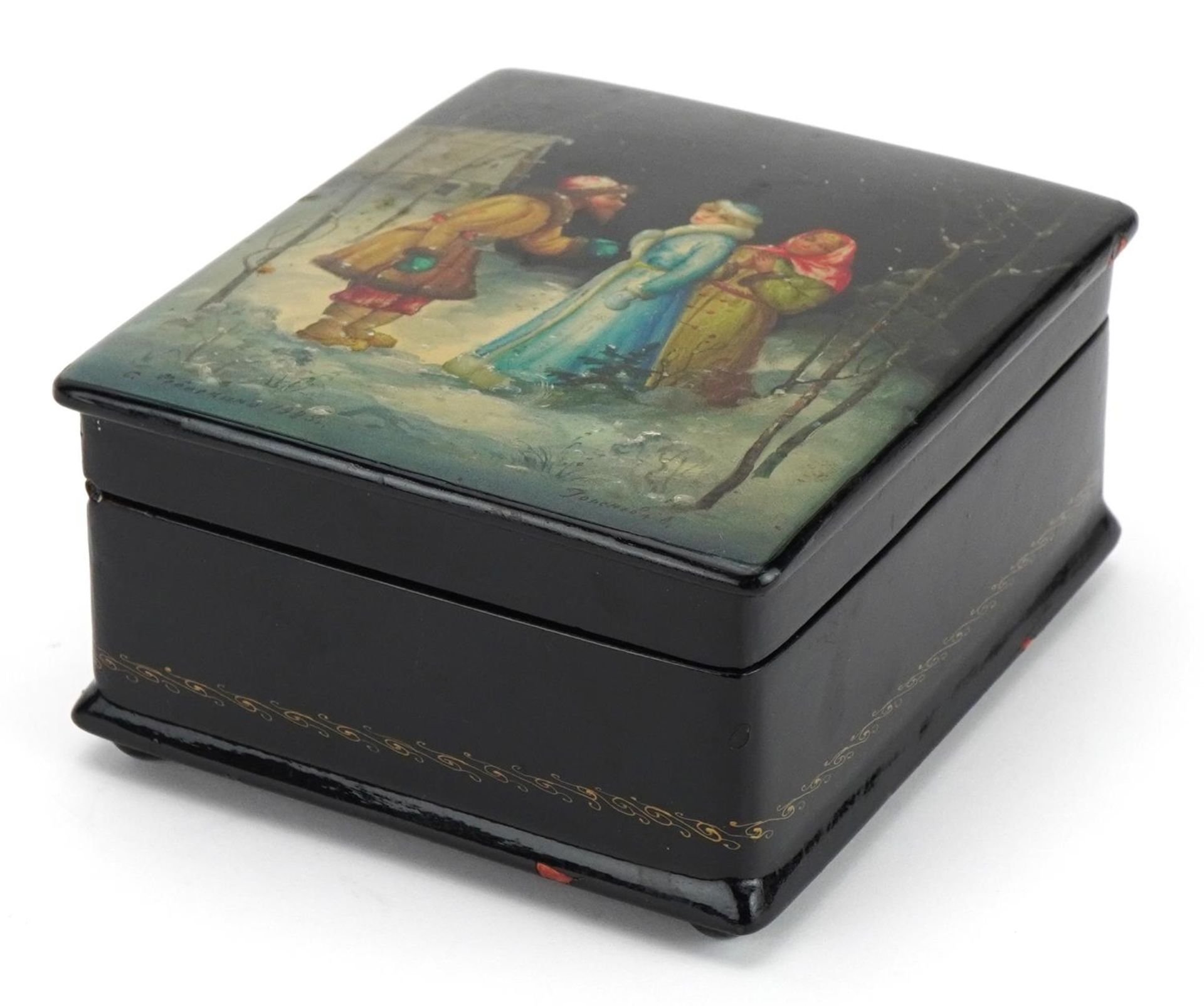 Russian papier mache lacquered box hand painted with figures before a snowy village, signed and