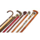 Seven walking sticks including a pool cue stick, one with horn handle and one bamboo with silver