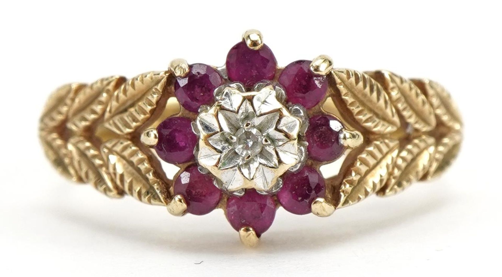 9ct gold ruby and diamond flower head ring, with leaf design shoulders, London 1987, size N, 2.8g