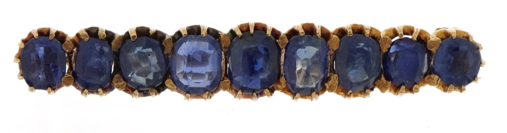 Unmarked gold sapphire brooch set with nine graduated stones housed in a velvet box, the largest