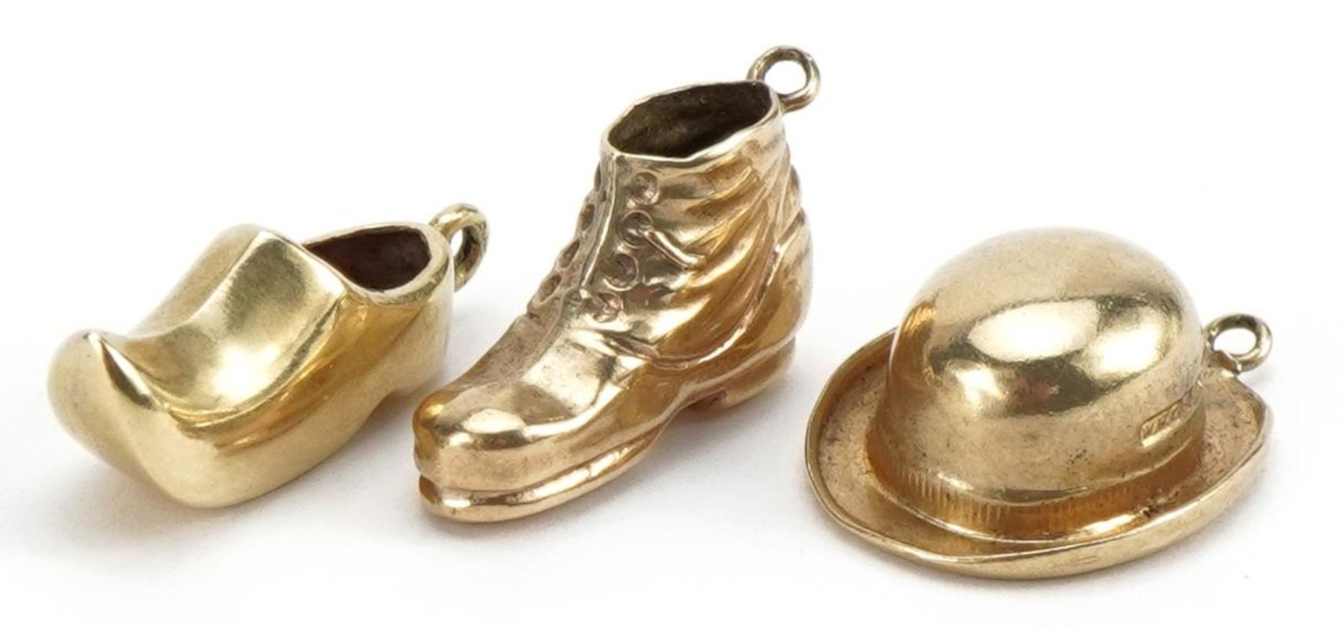 Three 9ct gold charms comprising boots, clog and bowler hat, the largest 1.6cm wide, total 1.8g