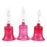 Three Victorian cranberry glass bells, the largest 33cm high