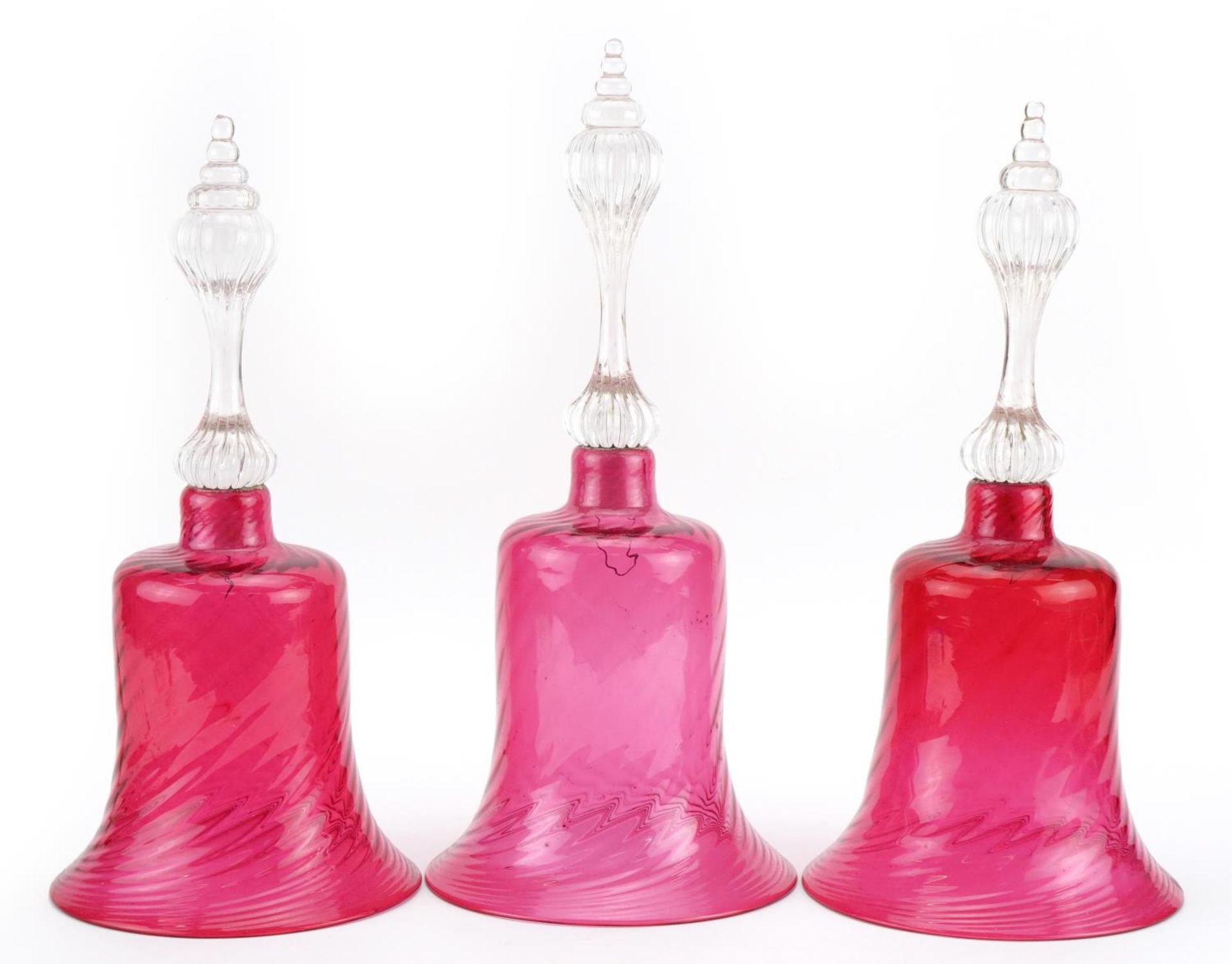 Three Victorian cranberry glass bells, the largest 33cm high