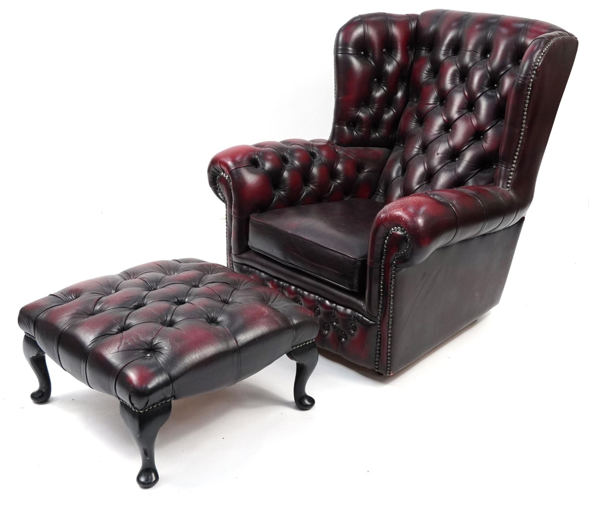 Oxblood leather button back wingback armchair with similar footstool, 91cm high