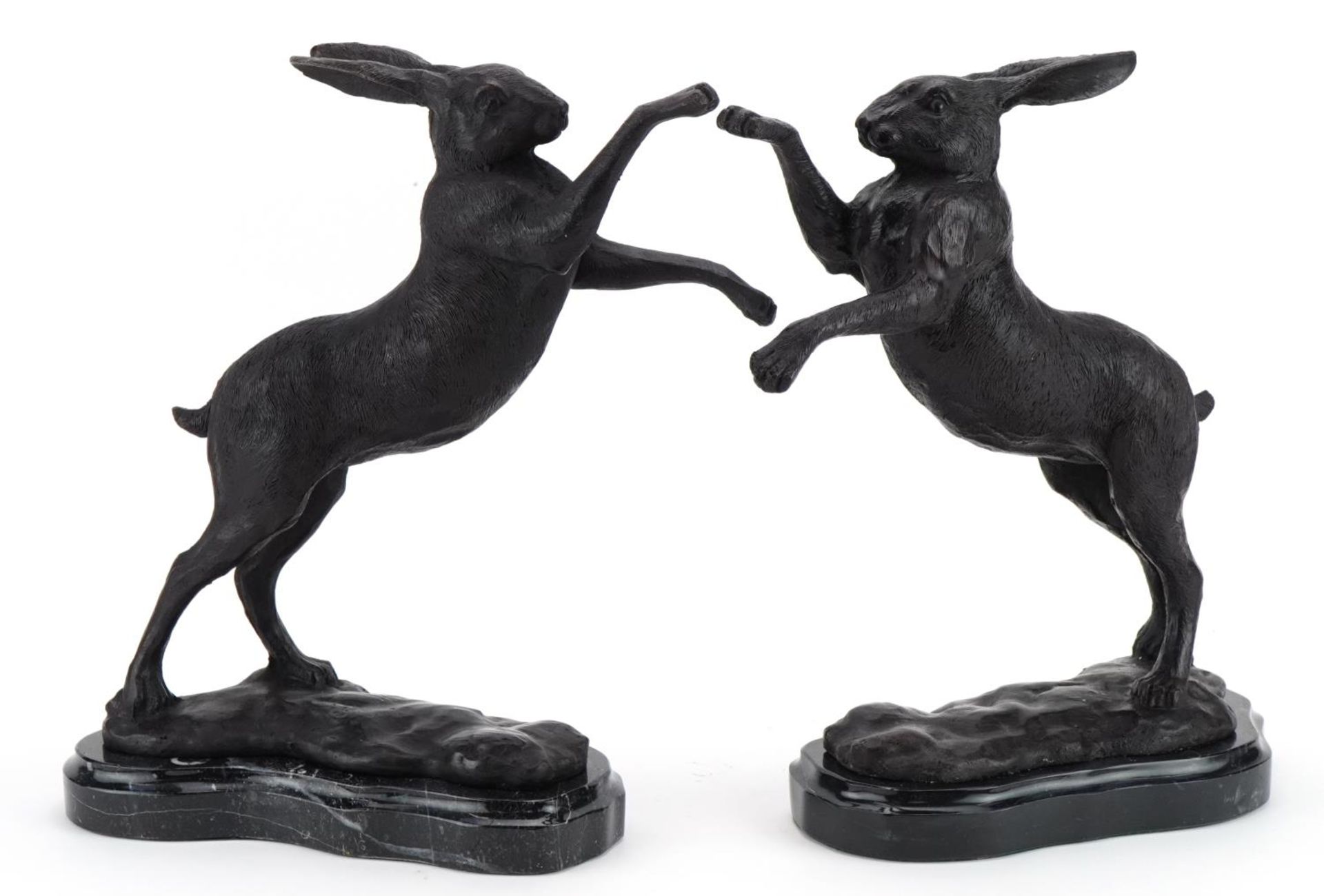 Pair of patinated bronze boxing hares raised on marble bases, each 30cm high