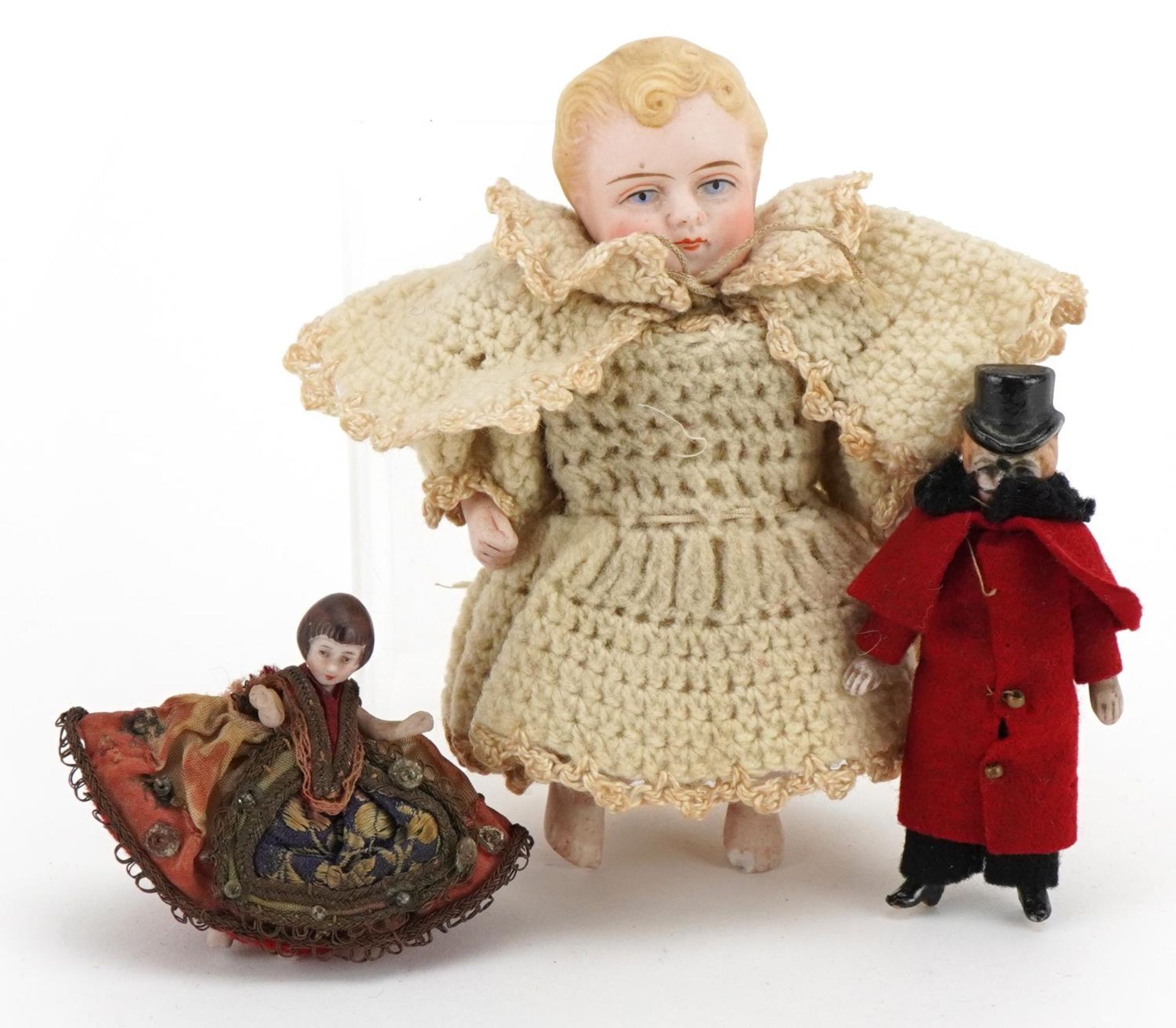 Three miniature bisque dolls with clothes, the largest 11cm high