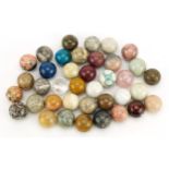 Collection of polished rock and mineral specimen orbs including rock crystal and rose quartz, each