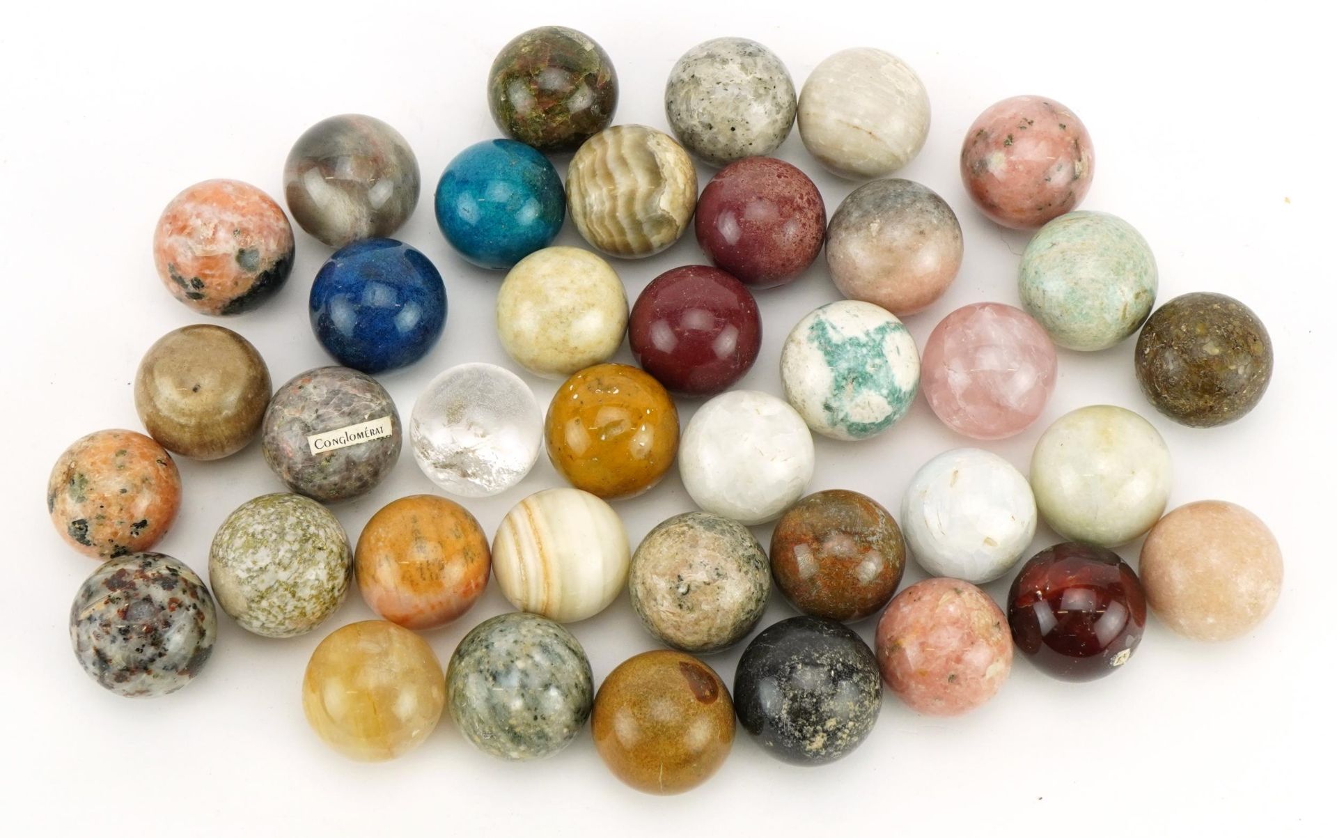 Collection of polished rock and mineral specimen orbs including rock crystal and rose quartz, each