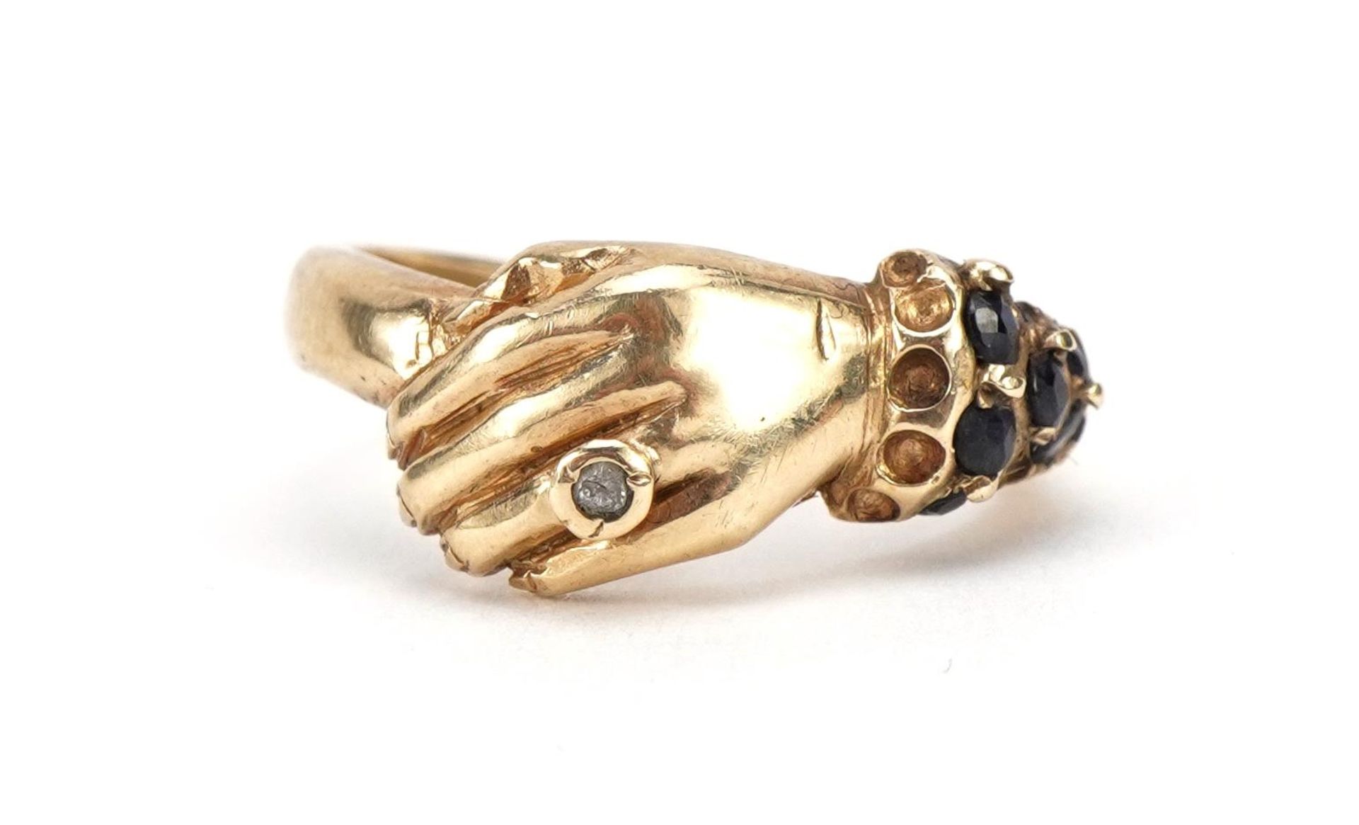 9ct gold clasped hand ring set with sapphires and a clear stone, size N/O, 3.5g