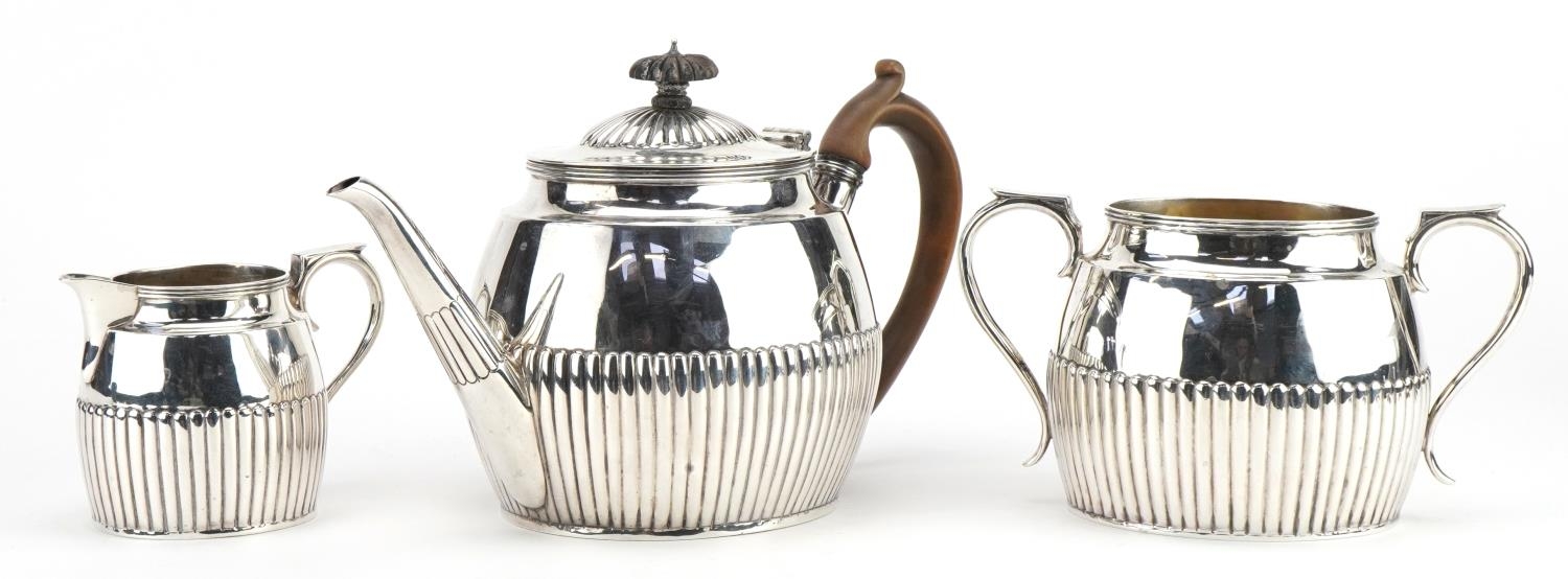 Lambert & Co, Victorian silver three piece tea service with demi fluted body, the teapot with wooden